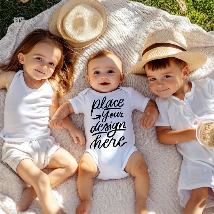 Three children lying on a blanket with one wearing a onesie that says 'place your design here'.